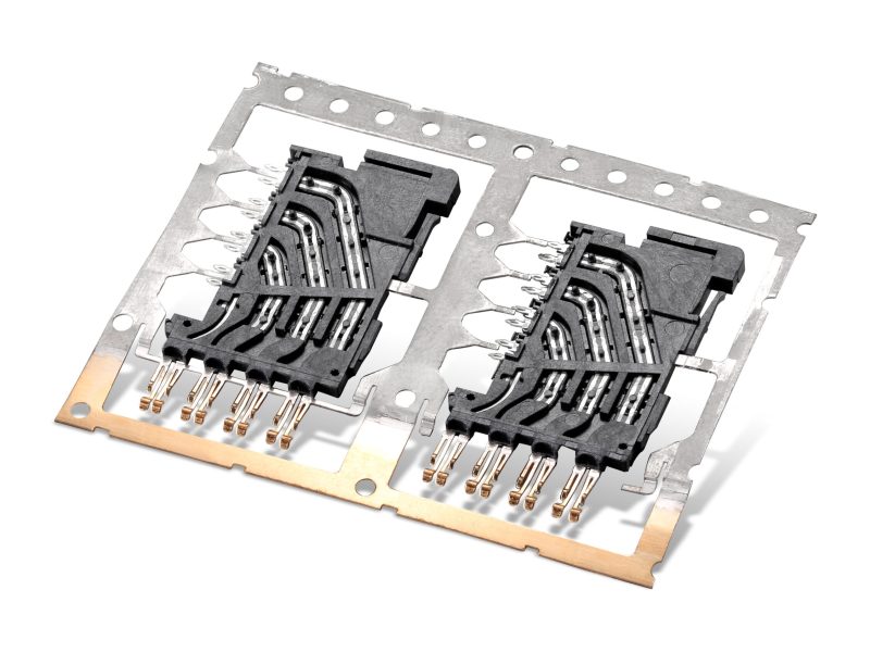 Custom stamped metal contacts insert-molded into plastic connector housings on a carrier strip, made by SSP