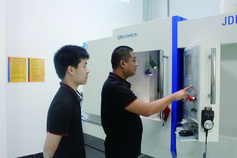 Two SSP engineers reviewing a machining program at a CNC machining center in the Dongguan plant